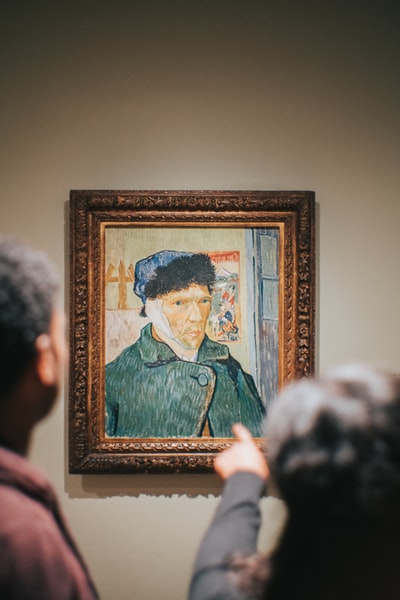 Two men stood beside the portrait of Vincent van gogh ears bandaged
